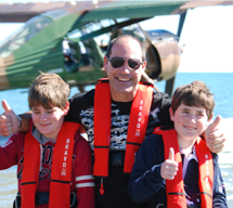 Father and two boys group hug after they have a seaplane adventure